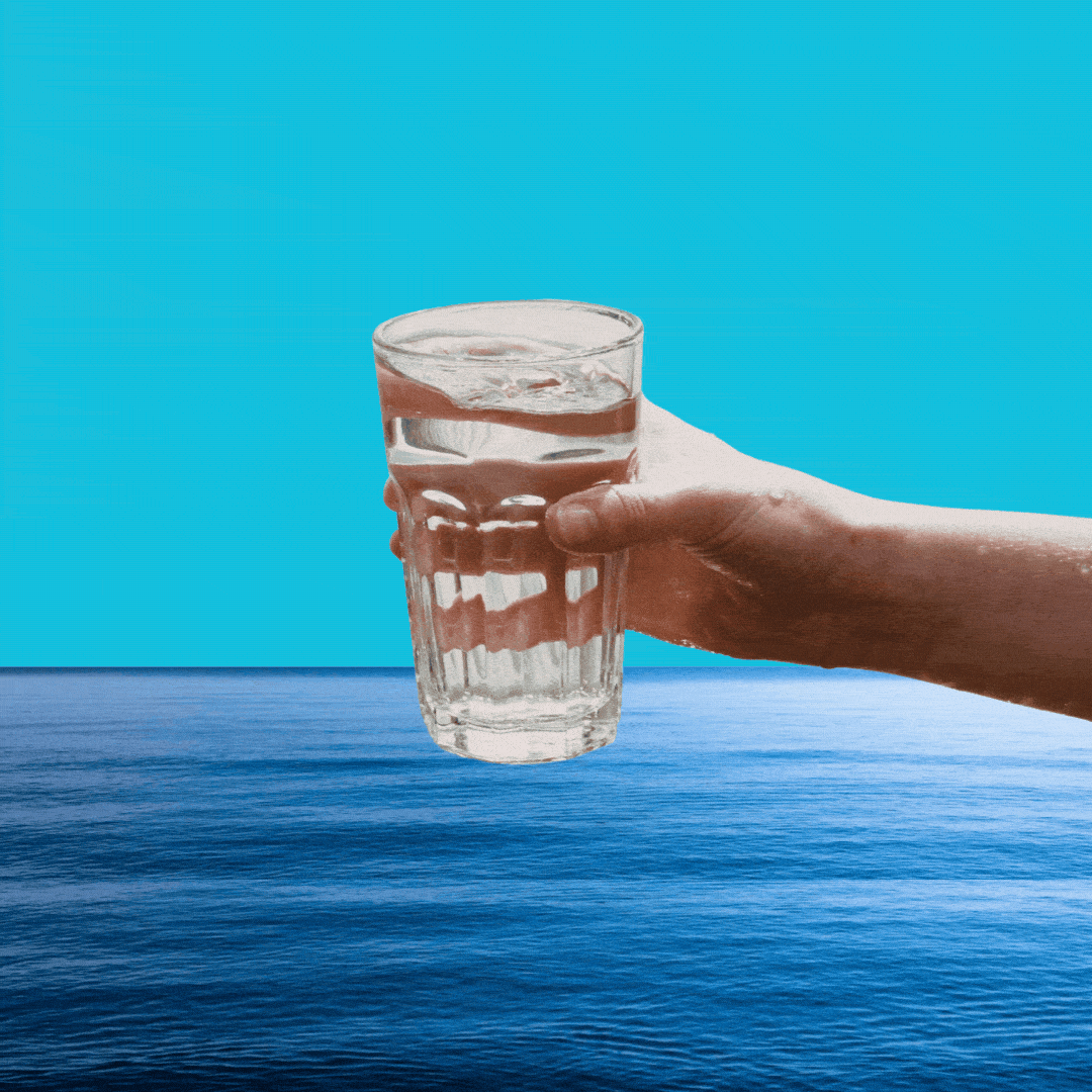 A glass of water being dipped into the ocean.
