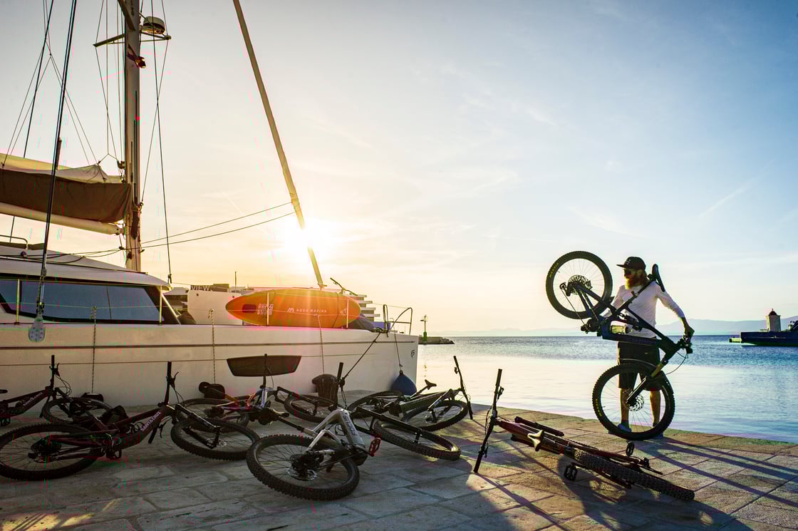 A man carries a mountain board on a dock near a boat.